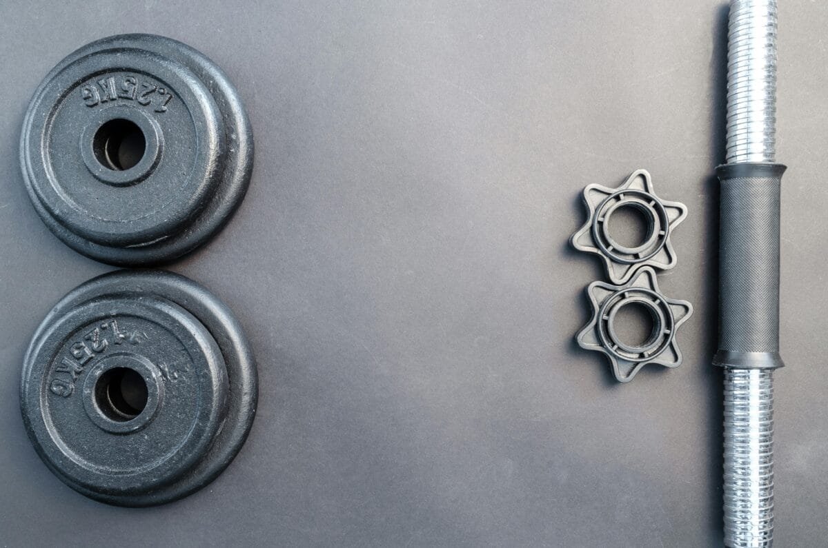 pexels-photo-669582-669582 Barbell and two dumbbell weights arranged on a neutral gray surface.