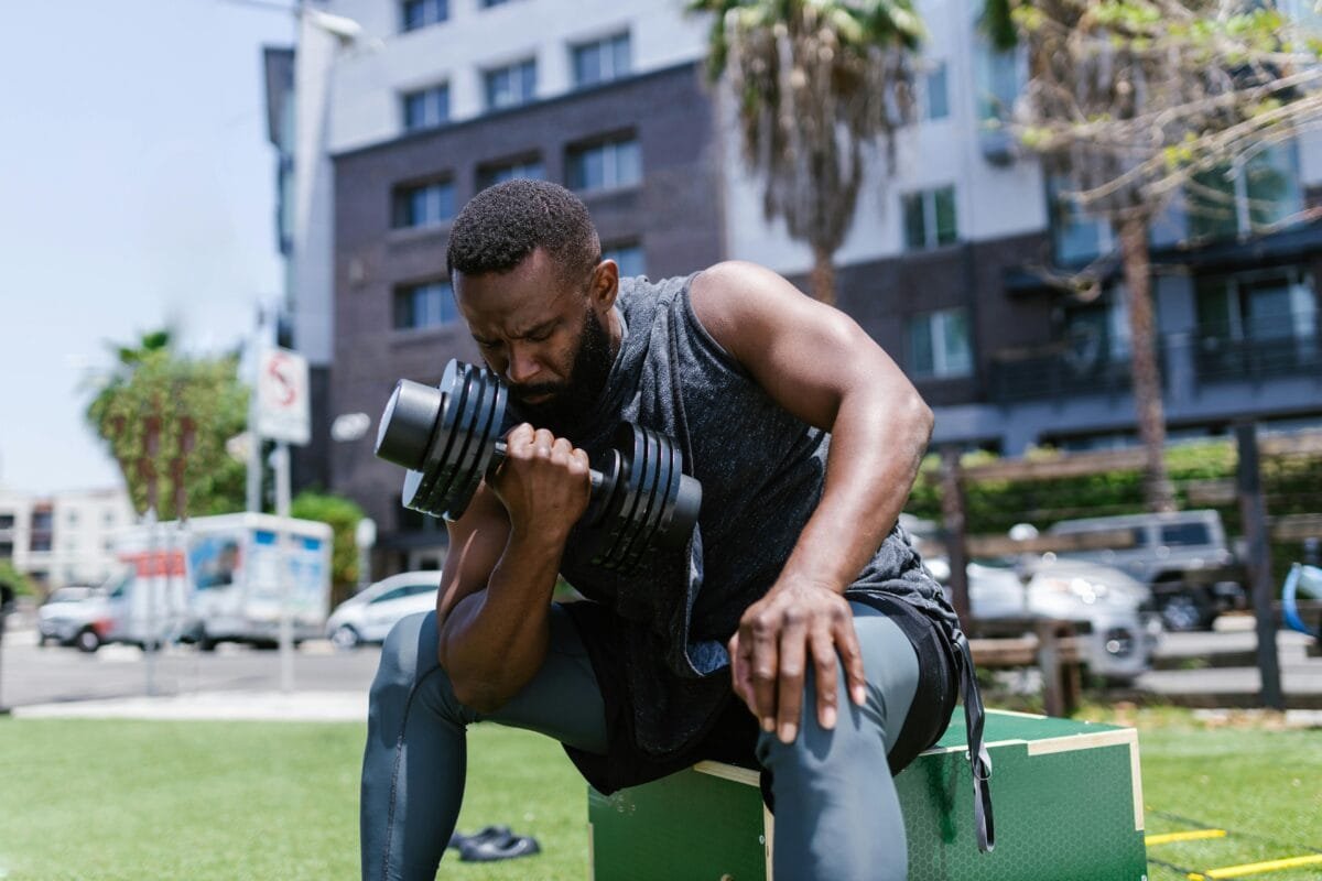 pexels-photo-8401861-8401861 Focused man working out with dumbbell in a city park, showcasing fitness and concentration.